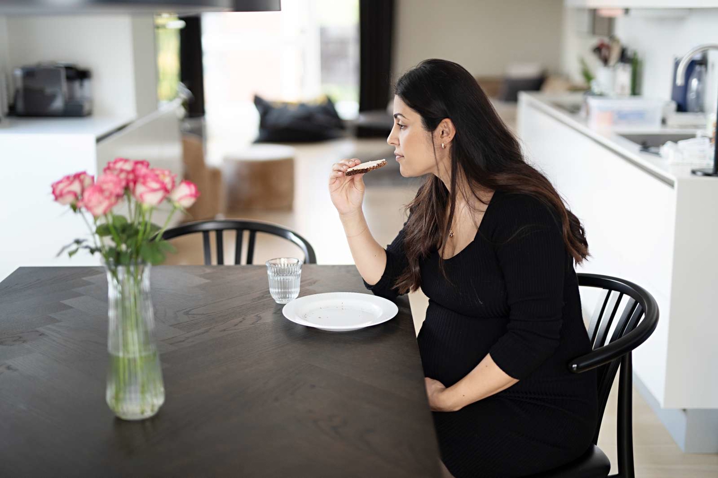Billede af en gravid kvinde, der spiser en rugbrødsmad.
