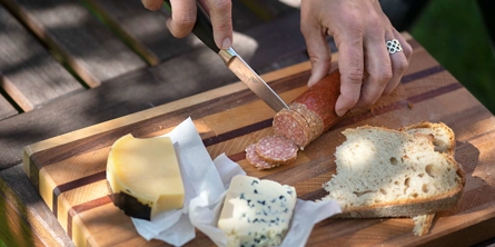 Billede af brød, ost, pølse og hænder.