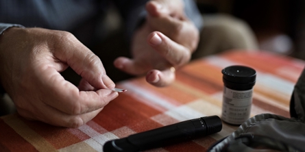 Billede af en fingerprikker og teststrimmel med bloddråbe