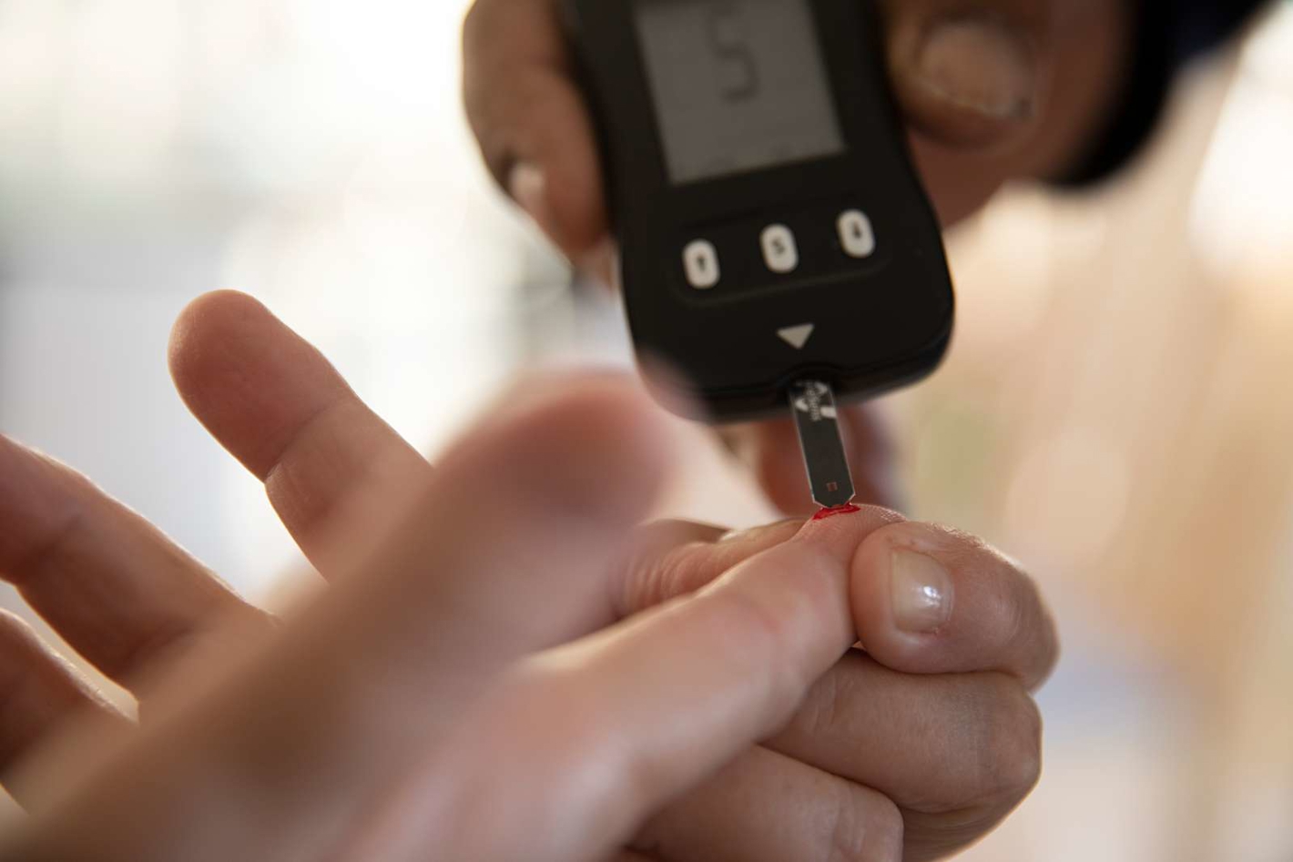 Billede af bloddråbe på finger og blodsukkermåling.