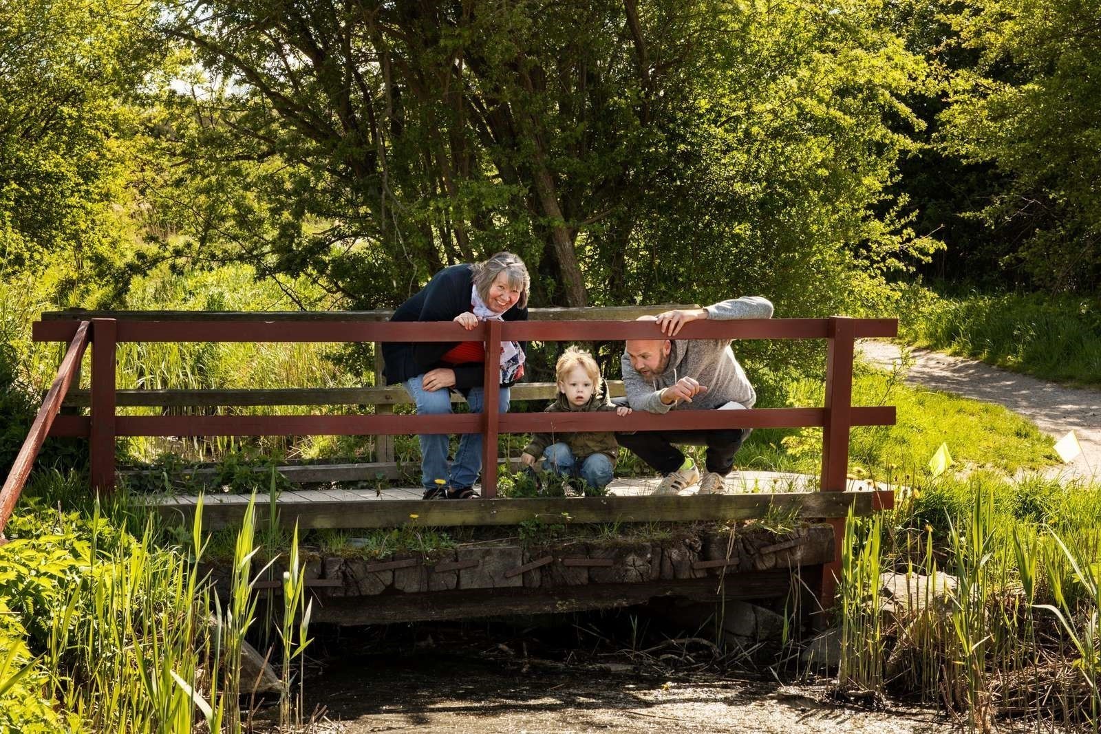 Billede af tre generationer på en lille bro i naturen
