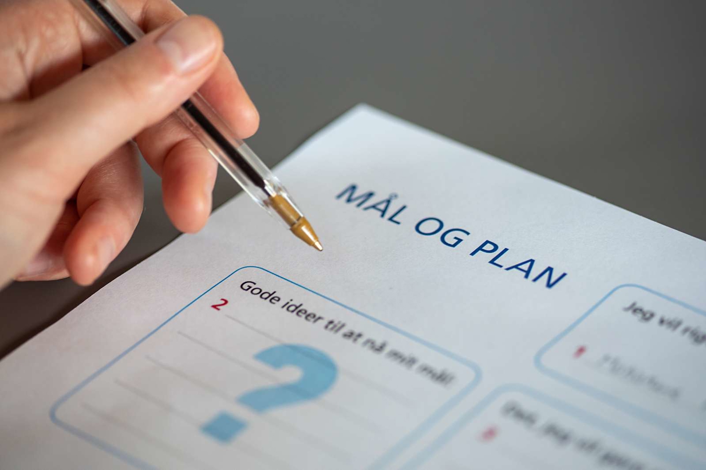 Billede af hånd og dokument, der handler om lægge en plan.