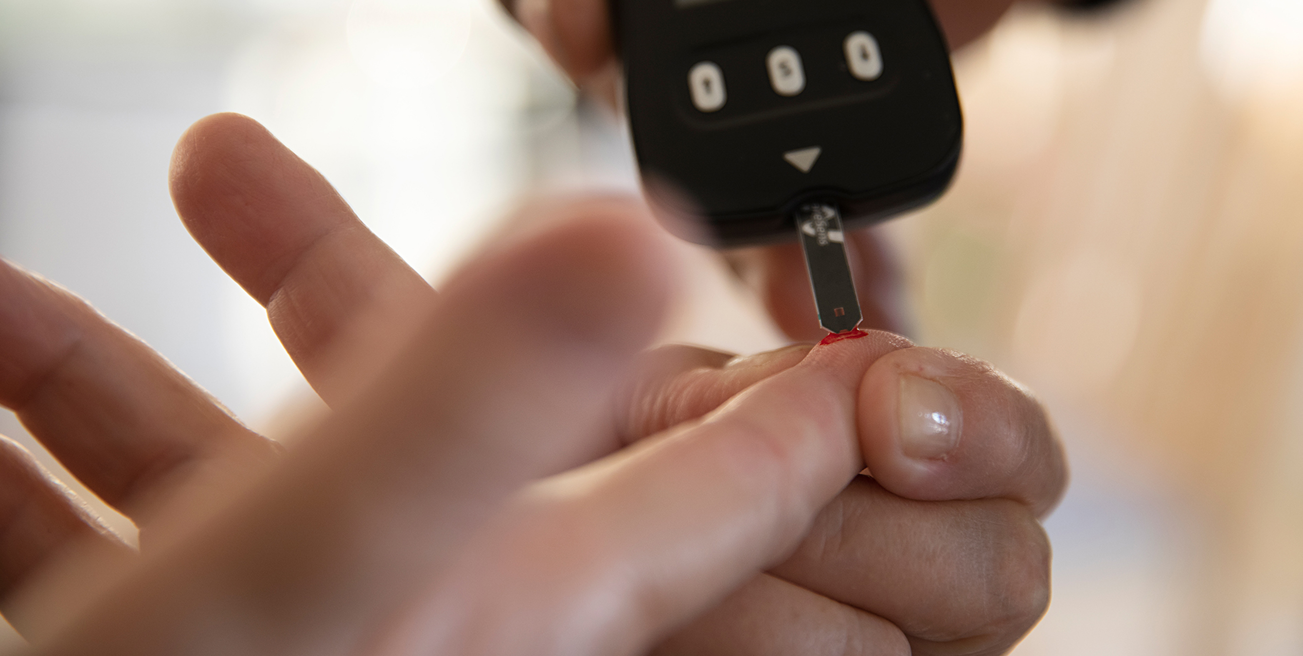 Billede af bloddråbe på finger og blodsukkermåling.