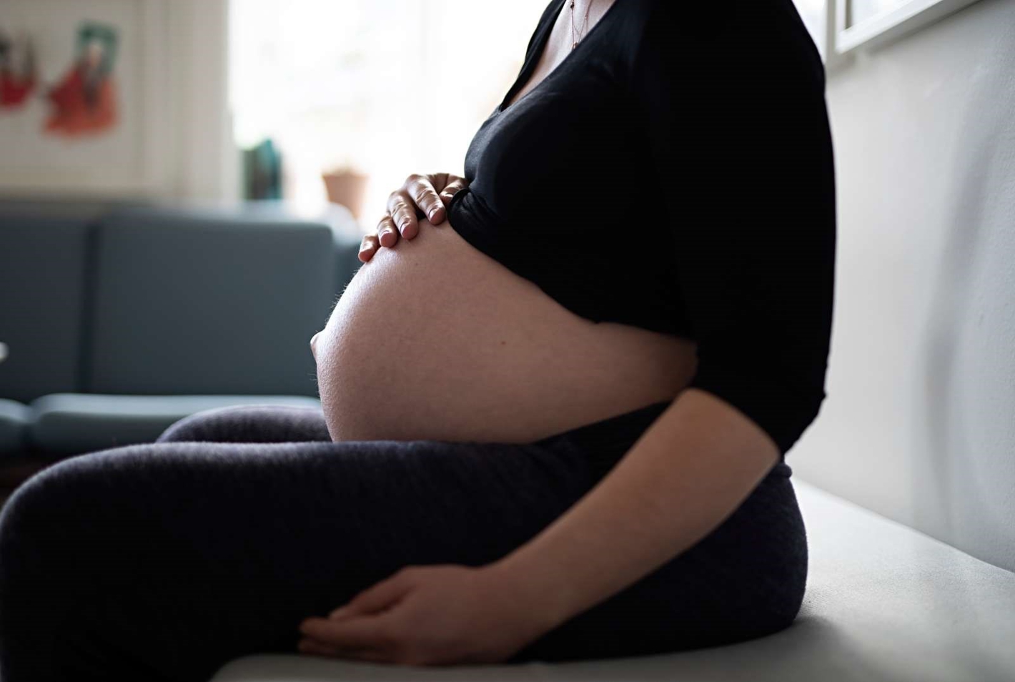 Billede af en gravid kvinde, der holder hånden på sin mave.